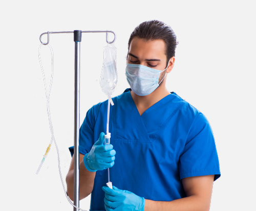 A nurse with a mask and gloves prepares an IV for Sylvant infusion.